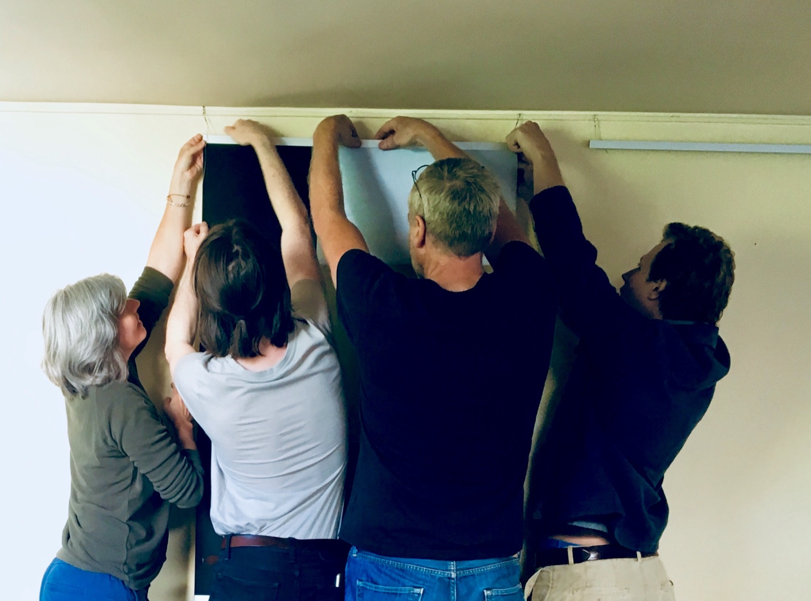 Quatre personnes accrochent ensemble un grand tirage au mur