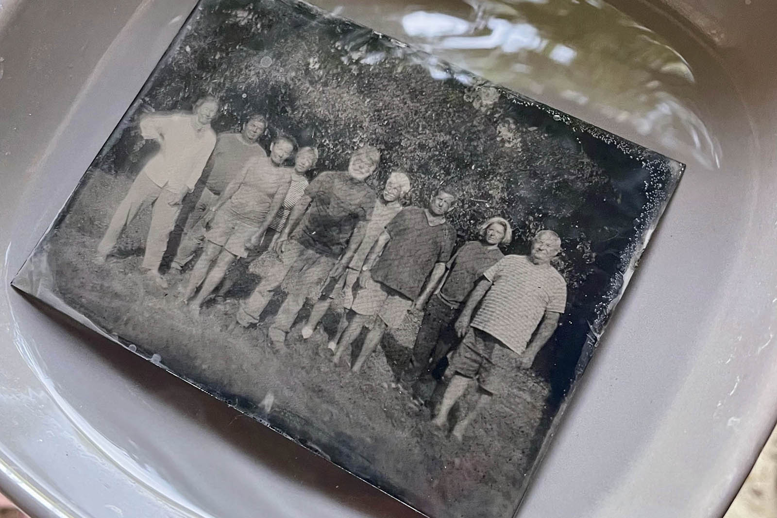 Ferrotype d’un groupe de personnes debout dans l’herbe, plongé dans une cuvette d’eau